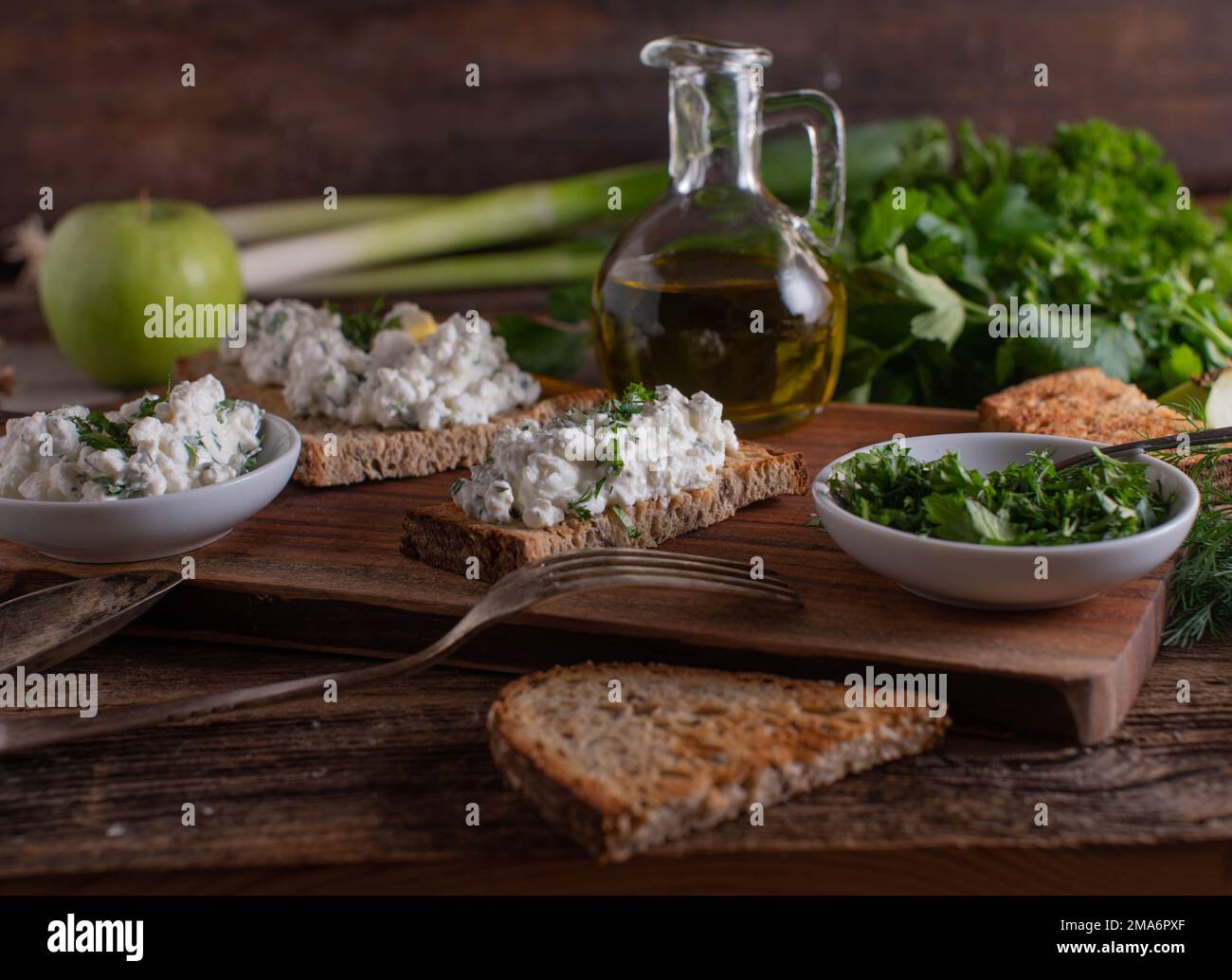 Pain de levain rôti avec salade de fromage cottage sur table en bois avec carafe à herbes et huile d'olive Banque D'Images