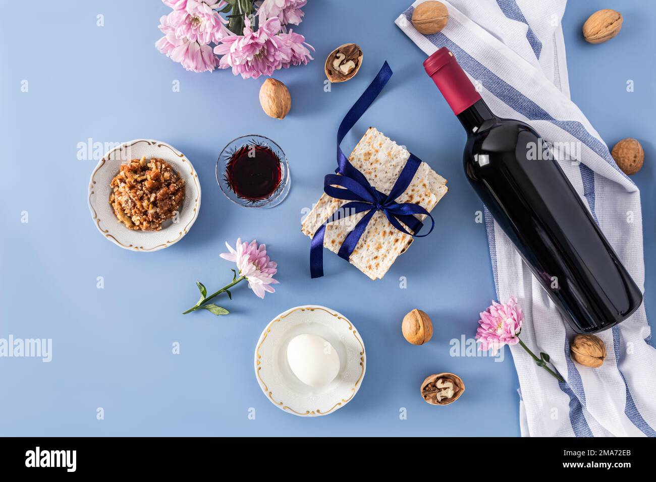 Magnifique fond bleu de la Pâque juive. vue de dessus d'une bouteille de vin casher rouge, verres de vin, matzah, noix, œuf sur une assiette Banque D'Images