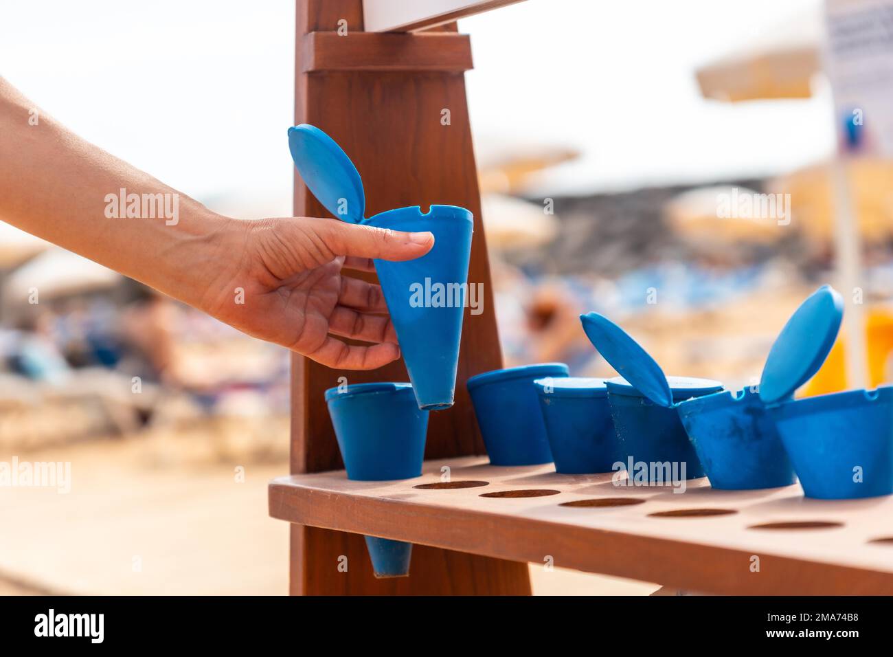 Une femme prenant un cendrier pour fumer sur la plage en été et ne pas jeter la cendre ou la cigarette sur le sable Banque D'Images