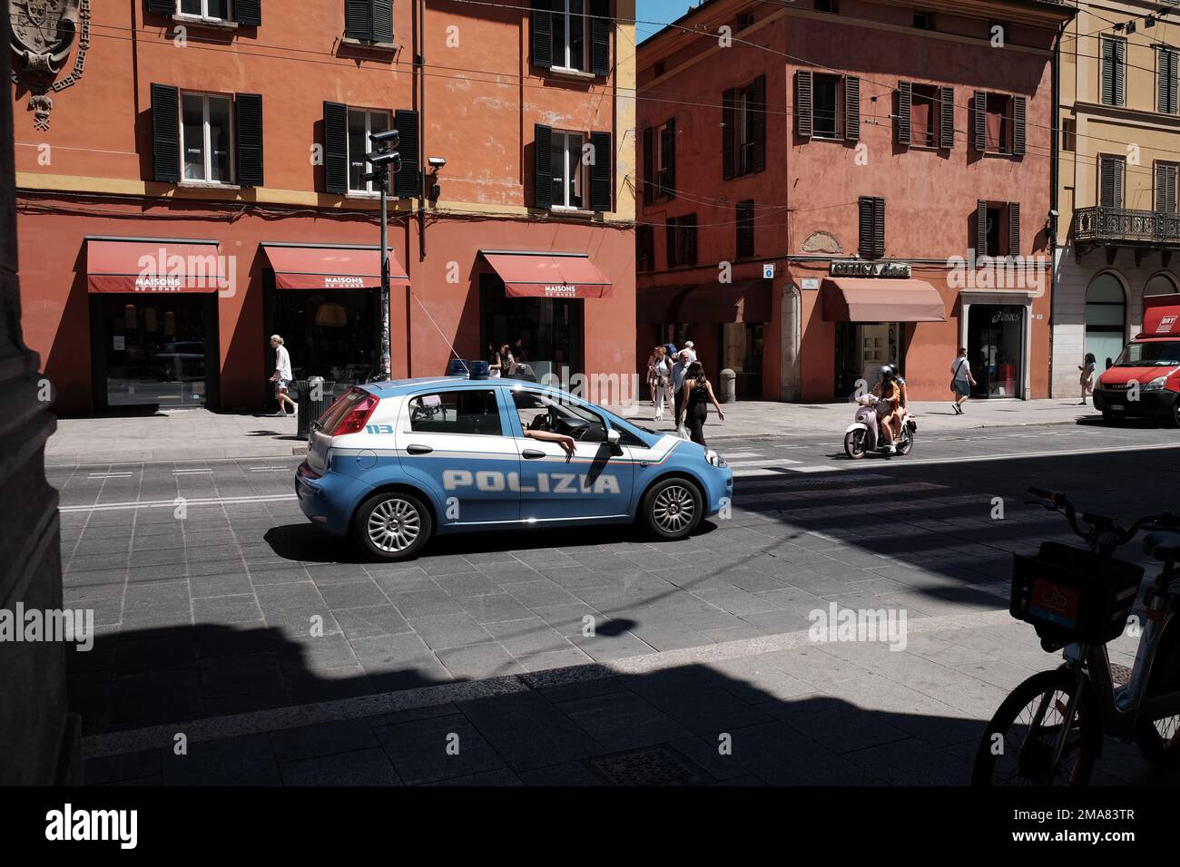 Une voiture de police italienne et une moto attendent à un croisement à Bologne, dans le nord de l'Italie, tandis qu'une dame traverse. Banque D'Images