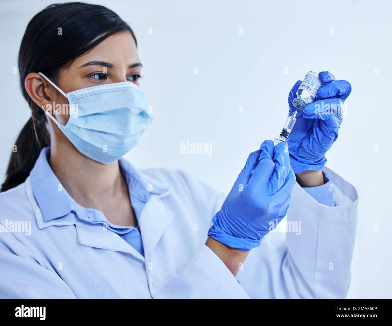 Préparation de votre vaccin. une jeune scientifique attirante utilisant une seringue pour extraire le vaccin covid 19 d'une bouteille dans son laboratoire. Banque D'Images