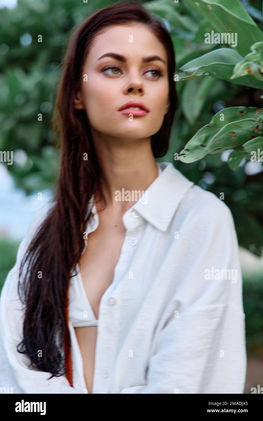 Portrait de beauté d'une femme avec des cheveux mouillés dans une chemise blanche près des feuilles d'un arbre tropical, beauté et la santé bronzée peau, le concept du visage Banque D'Images