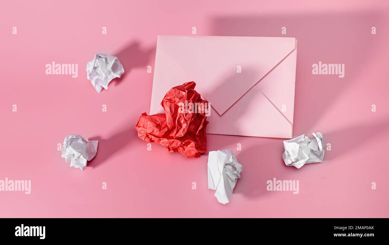 Coeur de papier et feuilles de papier froissés pour écrire avec une enveloppe artisanale.feuille de papier froissé en forme de coeur sur fond rose. Valen Banque D'Images
