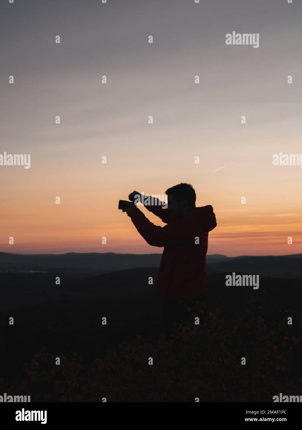 Silhouette d'un homme qui photographie le paysage au coucher du soleil. Banque D'Images