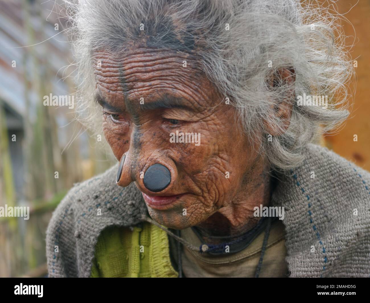 Ziro, Arunachal Pradesh, Inde - 02 19 2013 : Portrait de la pauvre femme tribale d'Apatani avec des tatouages faciaux traditionnels et des prises de nez regardant vers le bas Banque D'Images