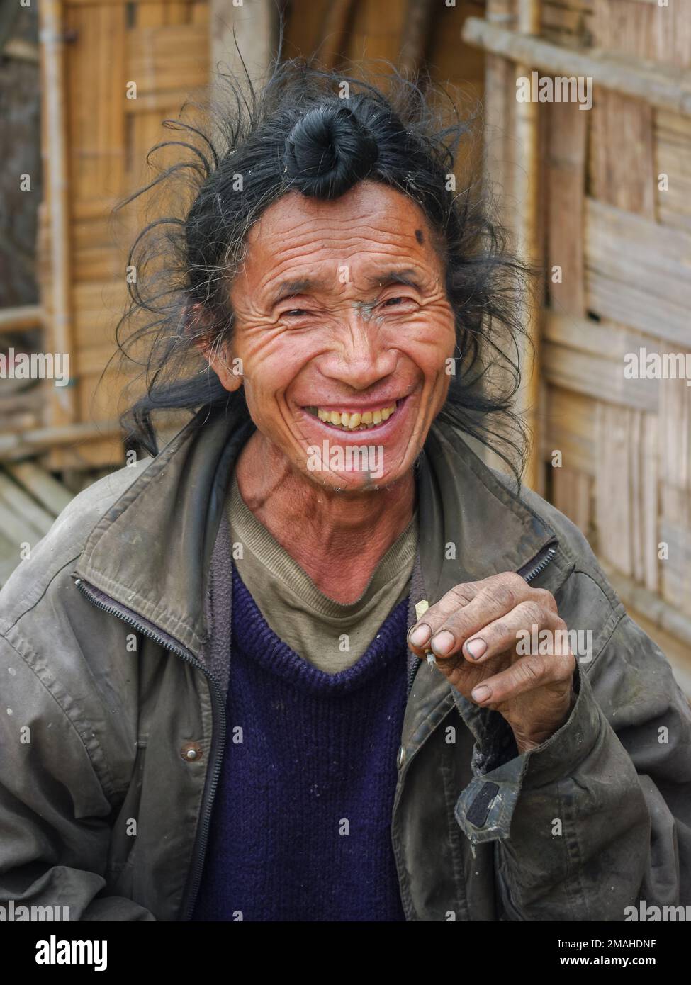 Ziro, Arunachal Pradesh, Inde - 02 24 2009 : Portrait d'un homme tribal Apatani souriant avec un pain et un tatouage au menton traditionnels Banque D'Images