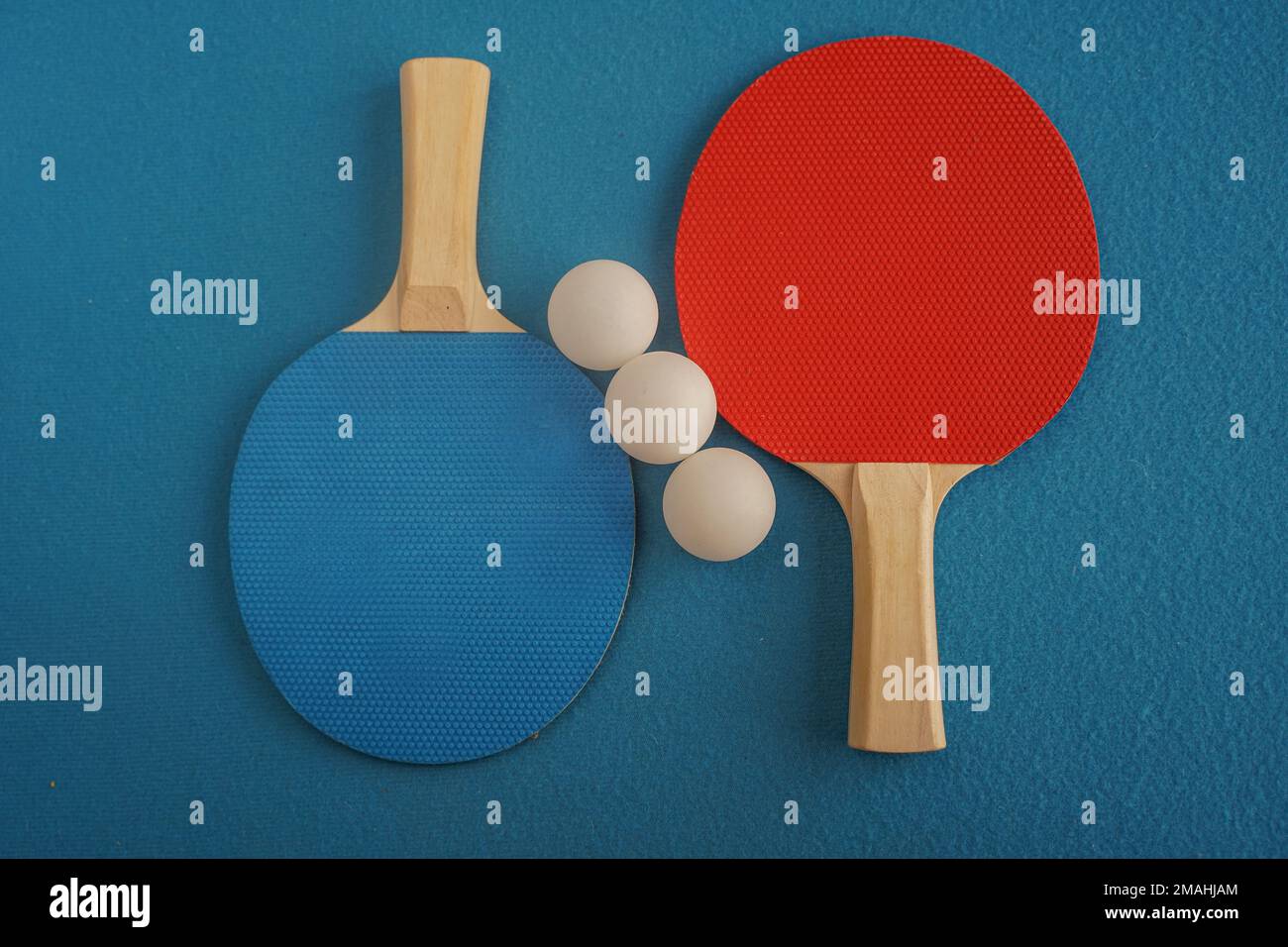 Tennis de table rouge et bleu ou raquettes de ping-pong et trois balles se trouvent sur un fond bleu avec un gros plan Banque D'Images