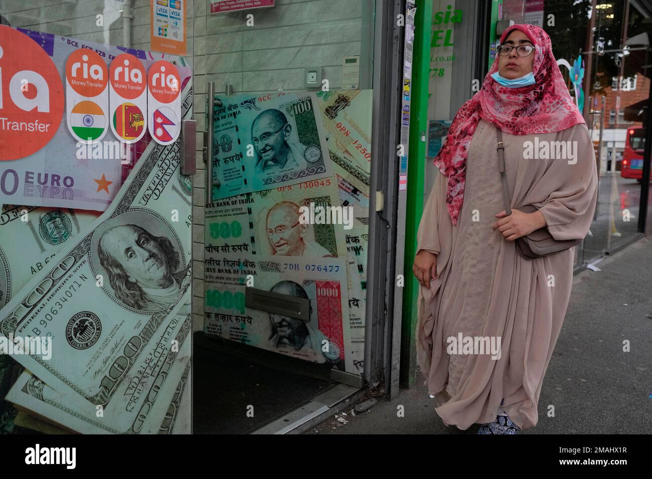 A woman walk past a money exchange shop in the district of Southall in  London, Tuesday, Sept. 13, 2022. In a church in a West London district  known locally as Little India,