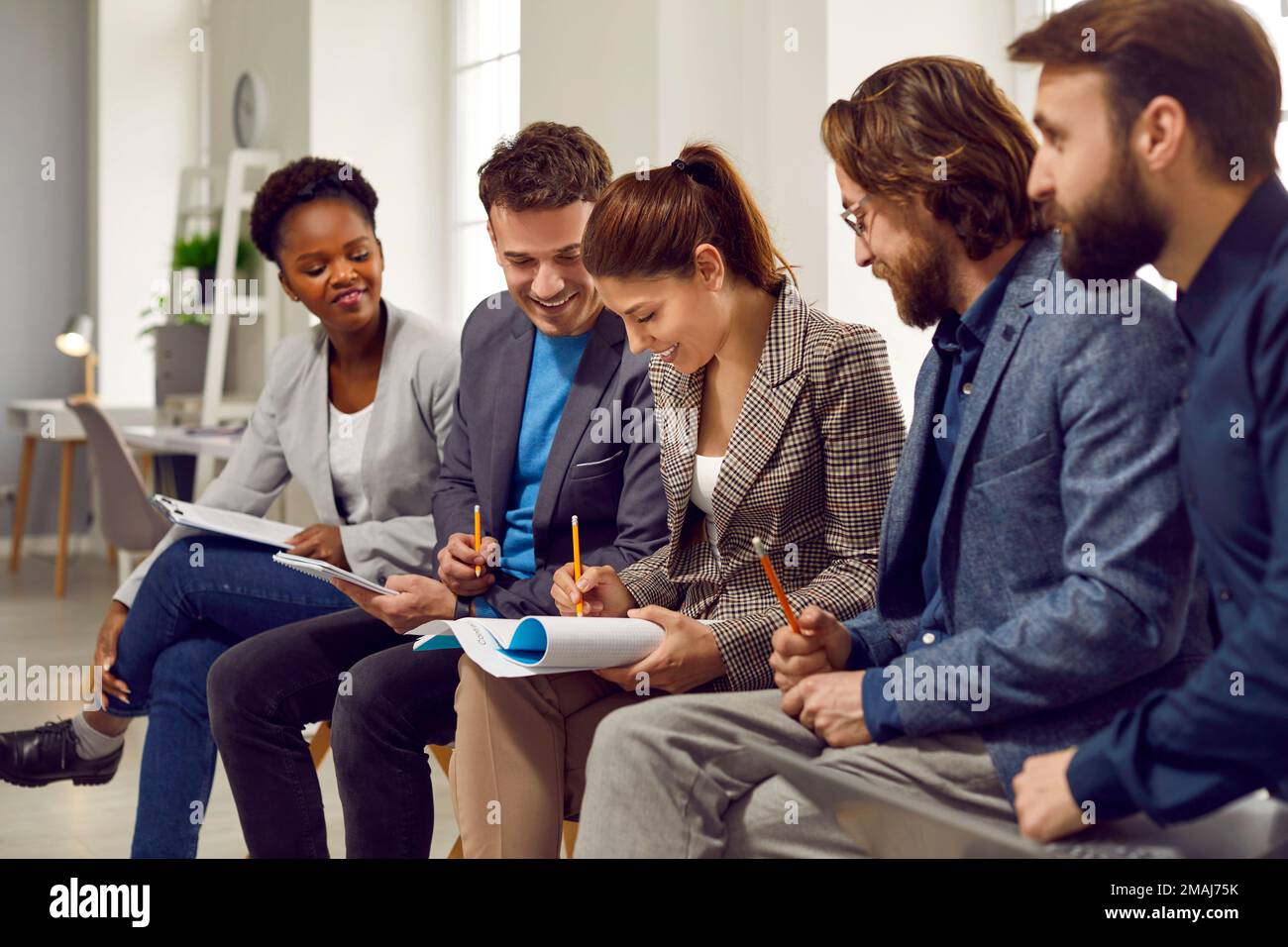 Équipe de personnes créatives et heureuses qui rédigeant des idées tout en travaillant ensemble sur un projet d'entreprise Banque D'Images