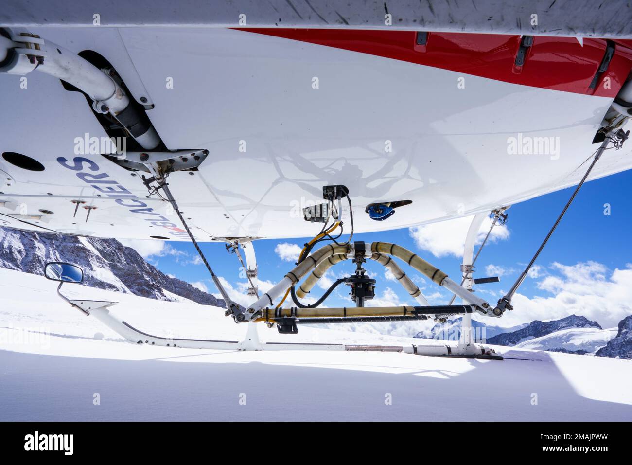 Hélicoptère sous-jacent se dresse sur la neige, fond bleu ciel avec des nuages. Jungfrau Joch, Grindelwald, Suisse Banque D'Images