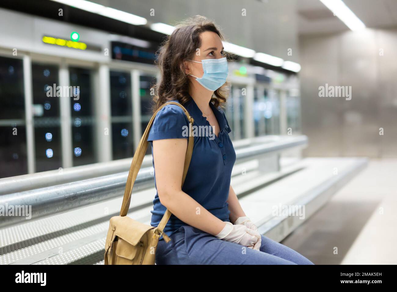 Brunette dans un masque médical en attente du métro Banque D'Images