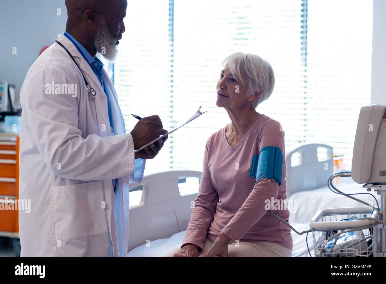 Divers médecin senior prenant la pression artérielle de la patiente senior à l'hôpital, espace de copie Banque D'Images