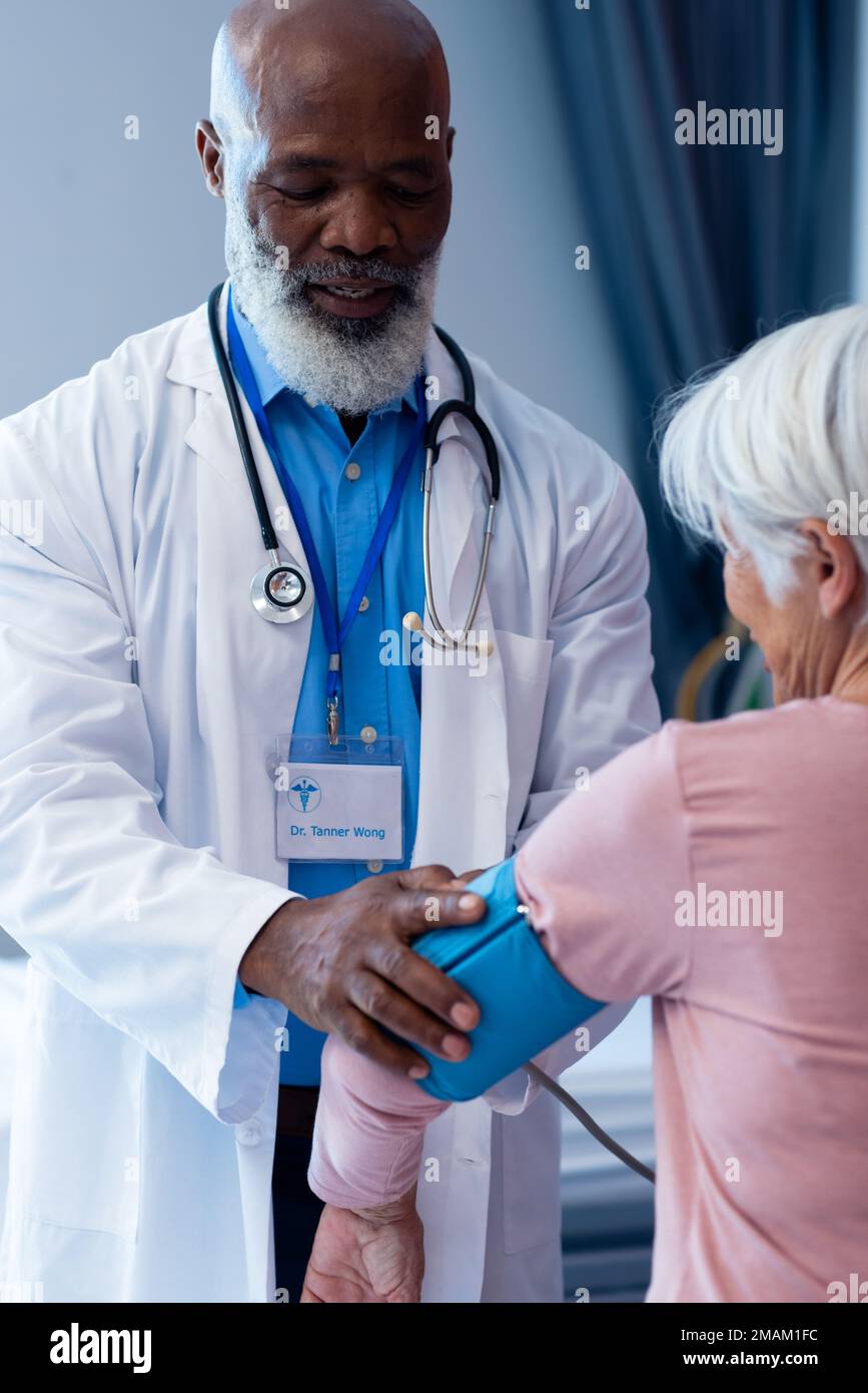 Vertical de heureux divers senior médecin prenant la pression artérielle de la femme patient, copier l'espace Banque D'Images
