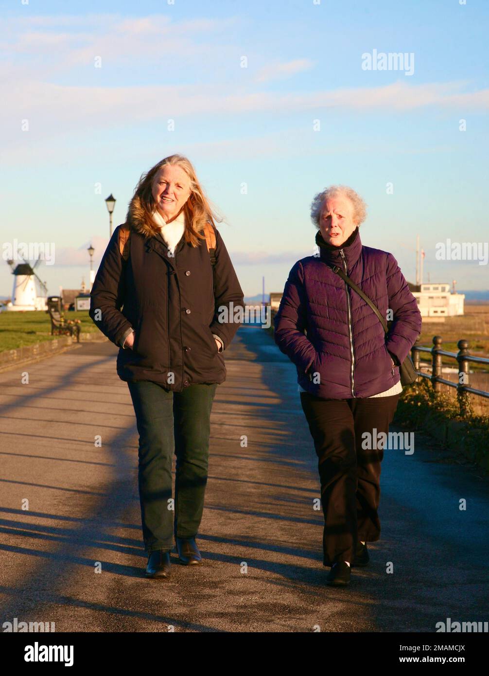 Deux femmes de haut niveau se promènent l'après-midi le long de la promenade, Lytham St Annes, Lancashire, Royaume-Uni, Europe Banque D'Images