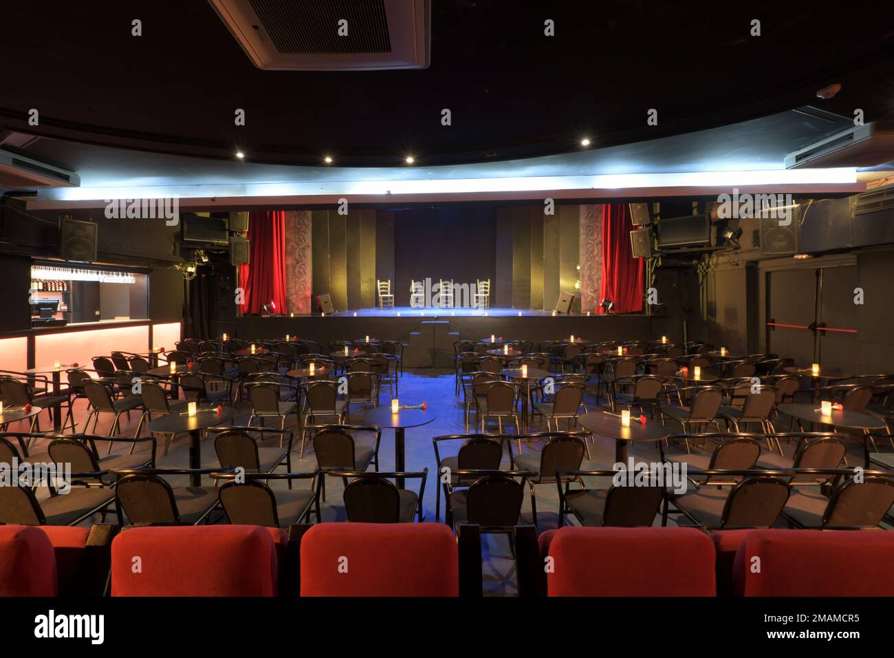 Un théâtre vide avec des étals avec des tables et une scène avec quatre chaises Banque D'Images Un théâtre vide avec des étals avec des tables et une scène avec quatre chaises Banque D'Images