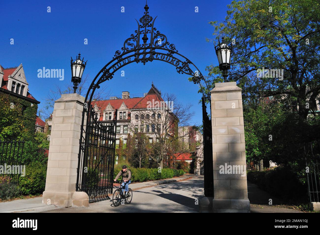 Chicago, Illinois, États-Unis. Un cycliste solitaire passe par Cobb Gate à l'extrémité sud de Hull court, sur le pittoresque campus de l'Université de Chicago. Banque D'Images