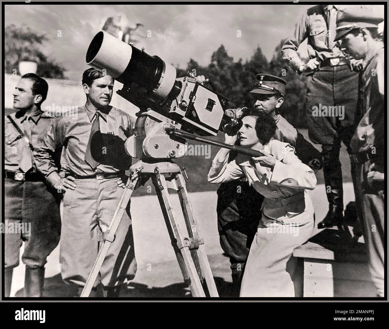 Leni Riefenstahl Directeur de film regardant à travers l'objectif d'une caméra pour le film de propagande nazi Triumph of the Wvolonté en 1934 sur le site de Reichsparteitagsgelände (lieu de rassemblement du parti nazi) à Nuremberg, en Franconie, en Allemagne. À gauche de la caméra, son cameraman en chef Sepp Allgeier (1895–1968) a gardé un œil sur elle. – Les membres de l'équipe de Riefenstahl portaient un uniforme sa ou des vêtements similaires (Allgeier) afin de conserver la vue d'ensemble du rallye, car les groupes déployés étaient tous en uniforme. Banque D'Images