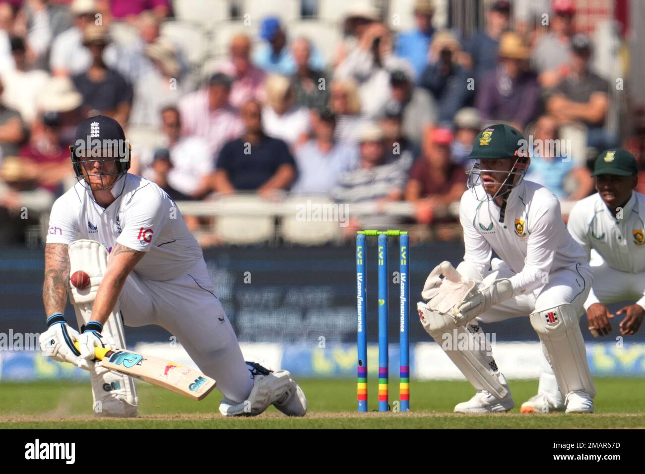 England's captain Ben Stokes, left, plays a reverse sweep as South Africa's Kyle Verreynne watches on during the second day of the 2nd test cricket match between England and South Africa at the Old Trafford, in Manchester, England, Friday, Aug. 26, 2022. (AP Photo/Jon Super) Banque D'Images