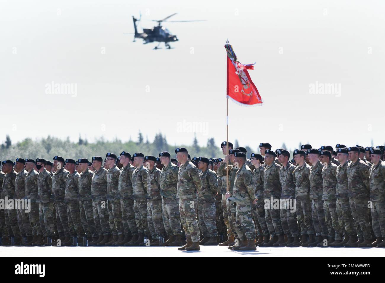 Des soldats se dressent en formation tandis qu'un hélicoptère Apache AH-64 survole pendant la cérémonie d'activation de la division aéroportée 11th à fort Wainwright, en Alaska, au 6 juin 2022. Les soldats ont échangé leurs parcelles de la Division d'infanterie de 25th contre celles de la division aéroportée historique de 11th et serviront en Alaska comme les « Anges arctiques », spécialisés dans les opérations par temps extrêmement froid et en terrain montagneux à haute altitude. (Photo de l'armée/John Pennell) Banque D'Images