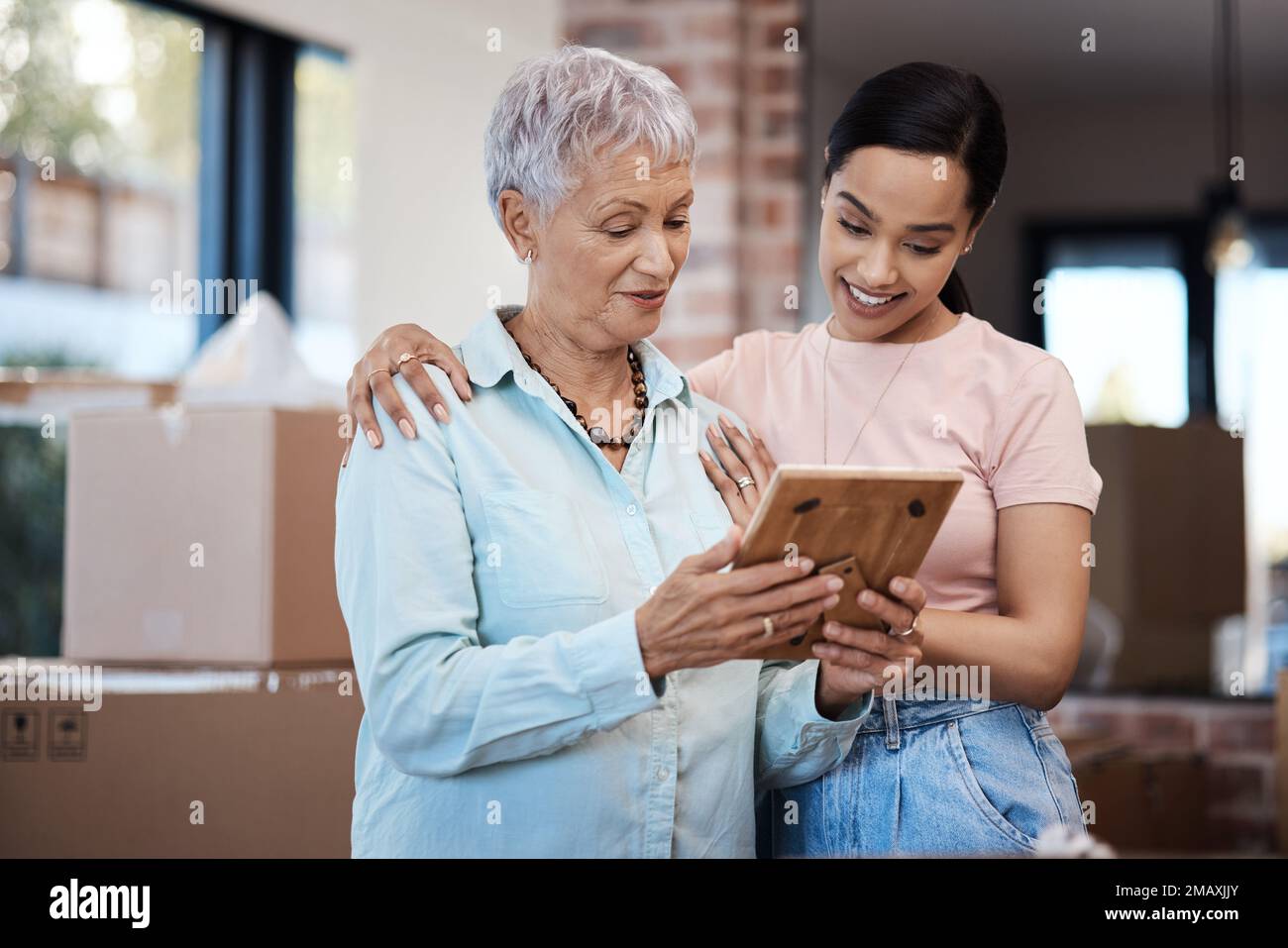 Une maison, tant de souvenirs. une femme âgée regardant une photo avec sa fille tout en emballant des boîtes le jour de déplacement. Banque D'Images