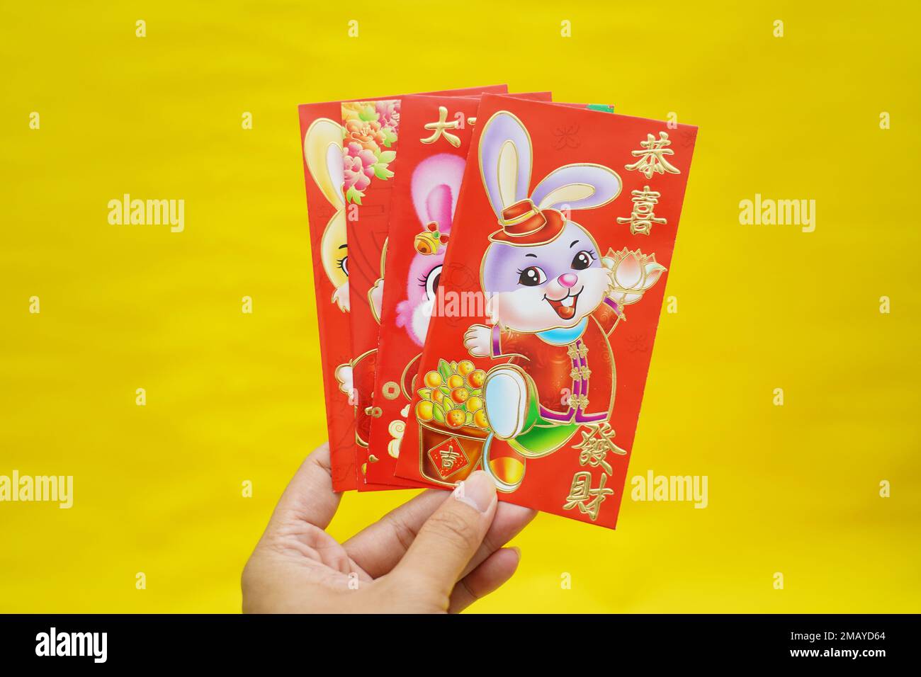 Enveloppes rouges à thème avec lapin, mots de bénédiction chinois sur fond jaune pour le nouvel an lunaire chinois. Bonjour 2023 année de lapin. Décoration Imlek. Banque D'Images