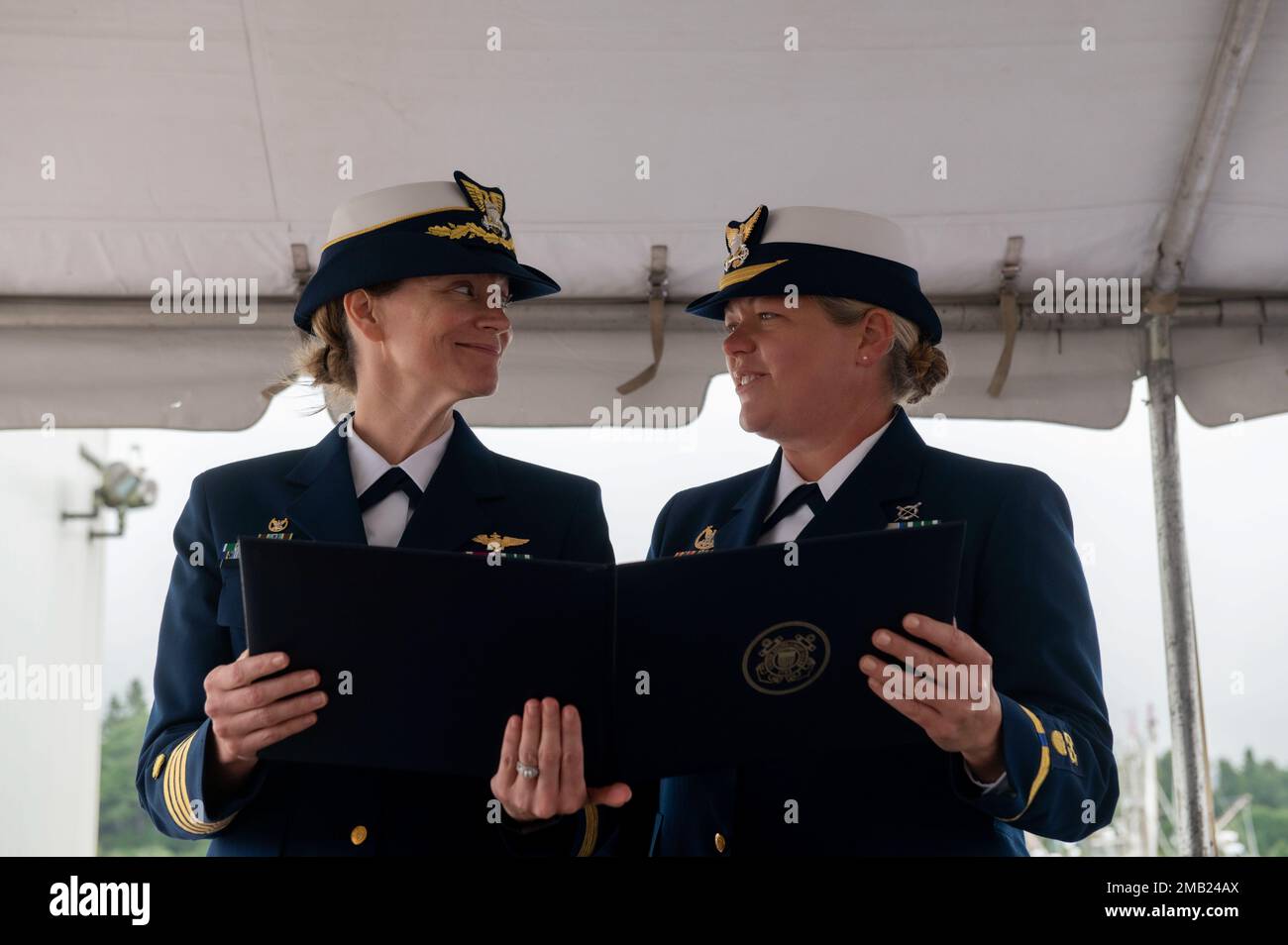 Le capitaine Breanna Knutson (à gauche), commandant du secteur de la Garde côtière, North Bend, lit un prix avec l'Adjudant-chef Beth Slade (à droite) lors de la cérémonie de passation de commandement de la station de la Garde côtière Coos Bay, à Coos Bay, en Oregon, le 10 juin 2022. L'Adjudant-chef Slade a été félicité pour ses efforts visant à aider une femme enceinte qui a contribué à l'amélioration de la rétention des femmes dans la Garde côtière. Banque D'Images