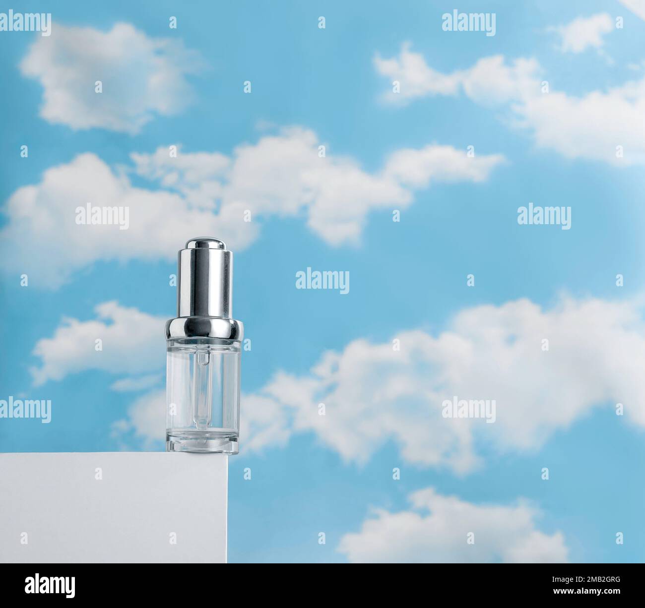 Sérum transparent sur podium blanc contre ciel bleu nuageux. Concept de légèreté des cosmétiques Banque D'Images