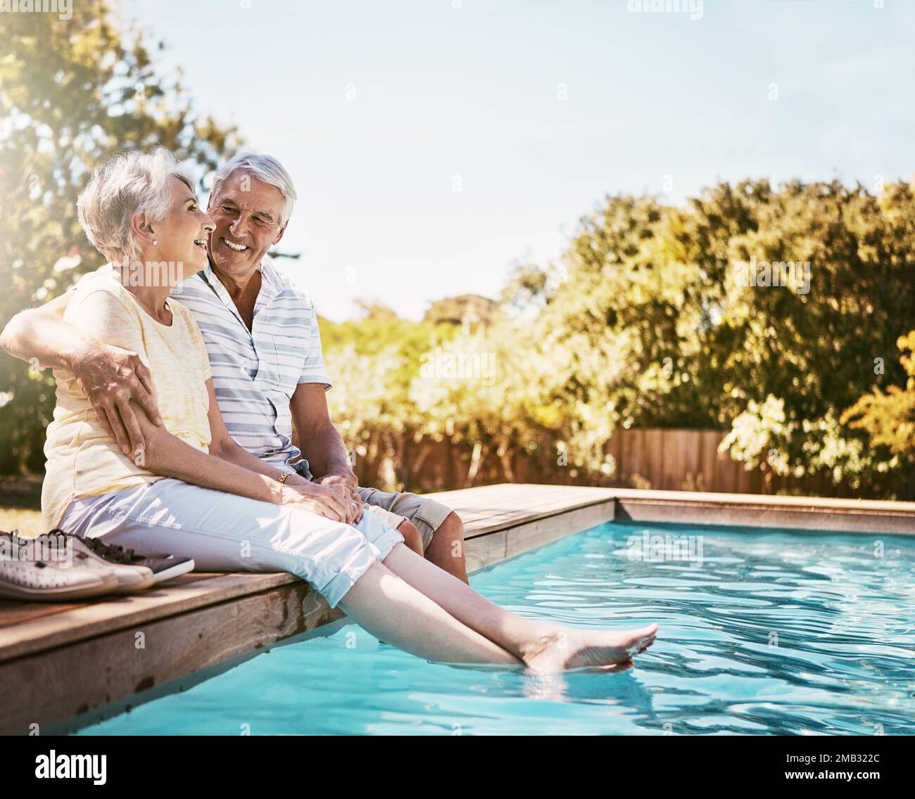 Couple senior, câlin et sourire près de la piscine pour se détendre, l'amour ou le temps de collage de qualité ensemble pendant les vacances d'été. Joyeux homme âgé tenant une femme Banque D'Images