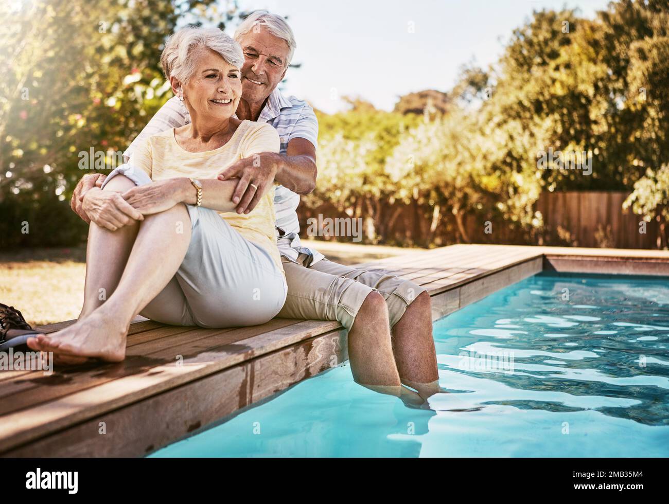 Couple senior, câlin et détendez-vous au bord de la piscine pour l'amour et les vacances d'été, de collage ou de qualité de temps ensemble dans le plein air. Bonne femme et homme âgé Banque D'Images