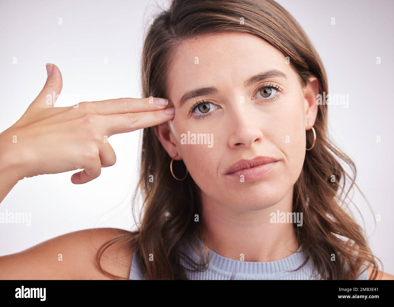 Sensation de vide. Portrait studio d'une jeune femme qui fait une arme à feu avec ses mains sur fond gris. Banque D'Images
