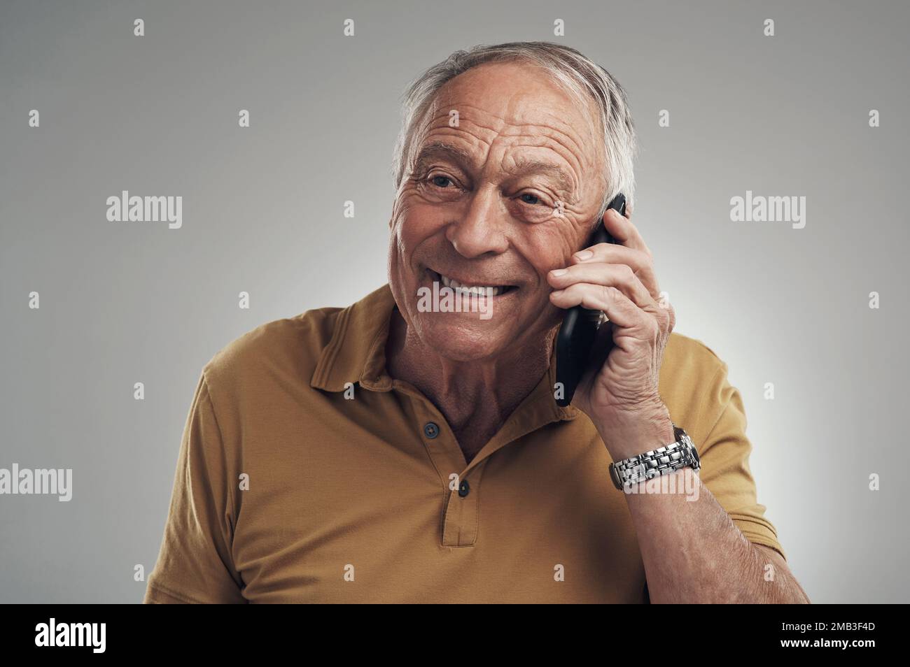 Bonjour mon amour. Studio photo d'un homme âgé utilisant son téléphone portable sur fond gris. Banque D'Images