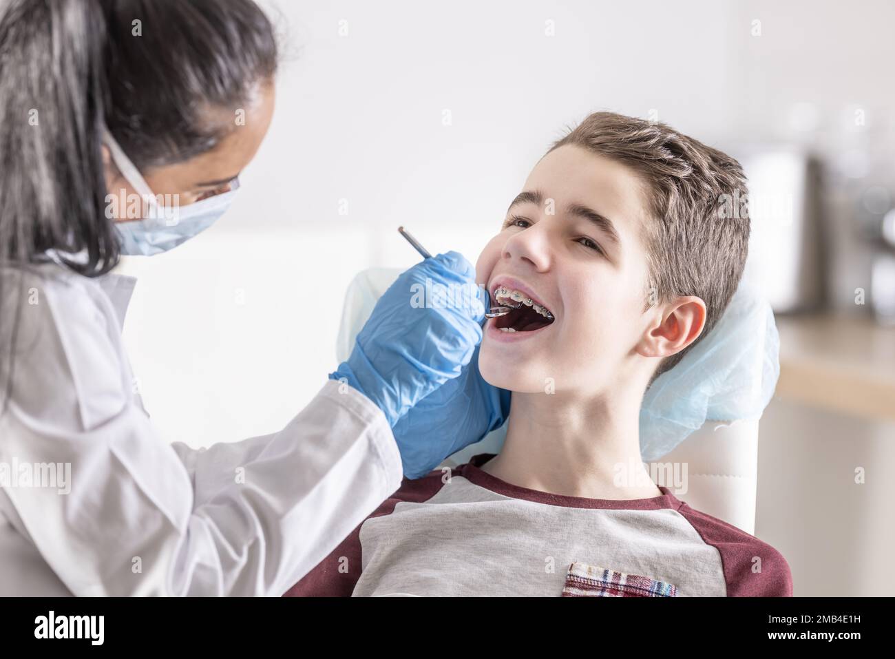 Le garçon est assis au dentiste, en vérifiant les bretelles dentaires. Banque D'Images