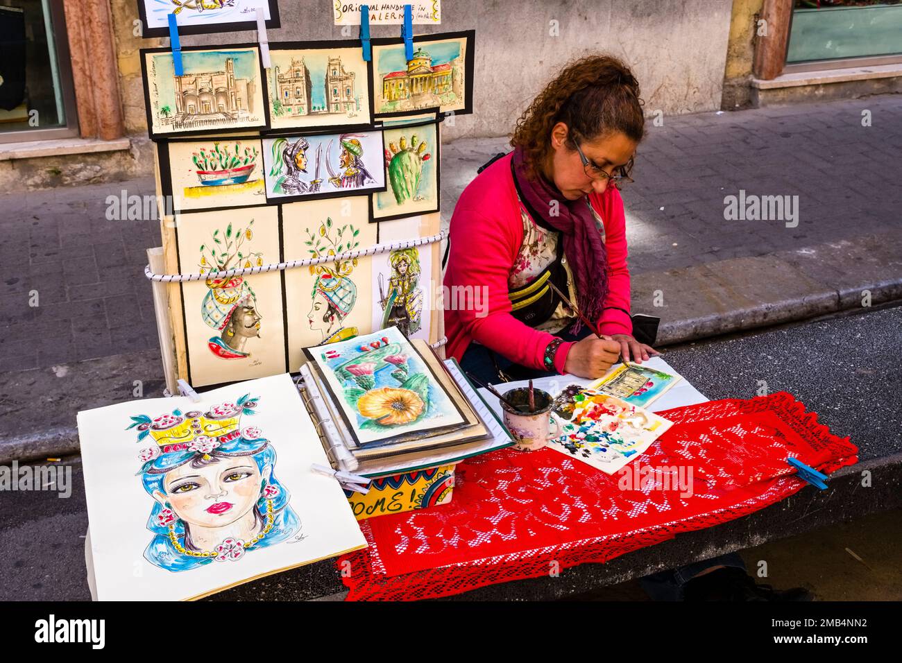 Un artiste fémal peint des peintures colorées dans les rues de l'une des banlieues de Palerme. Banque D'Images