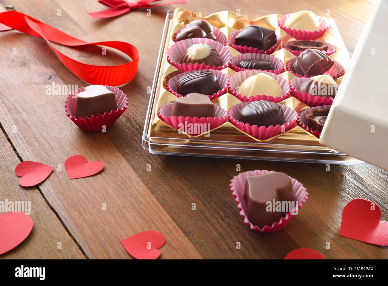Présentation d'un assortiment de chocolats avec des découpes en forme de cœur rouge sur une table en bois. Vue en hauteur. Banque D'Images