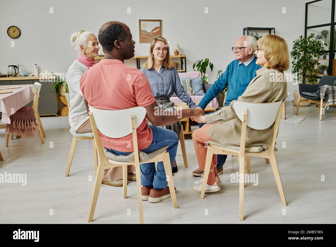 Les personnes âgées qui obtiennent du soutien à la séance de psychothérapie, elles sont assises en cercle et tiennent les mains Banque D'Images
