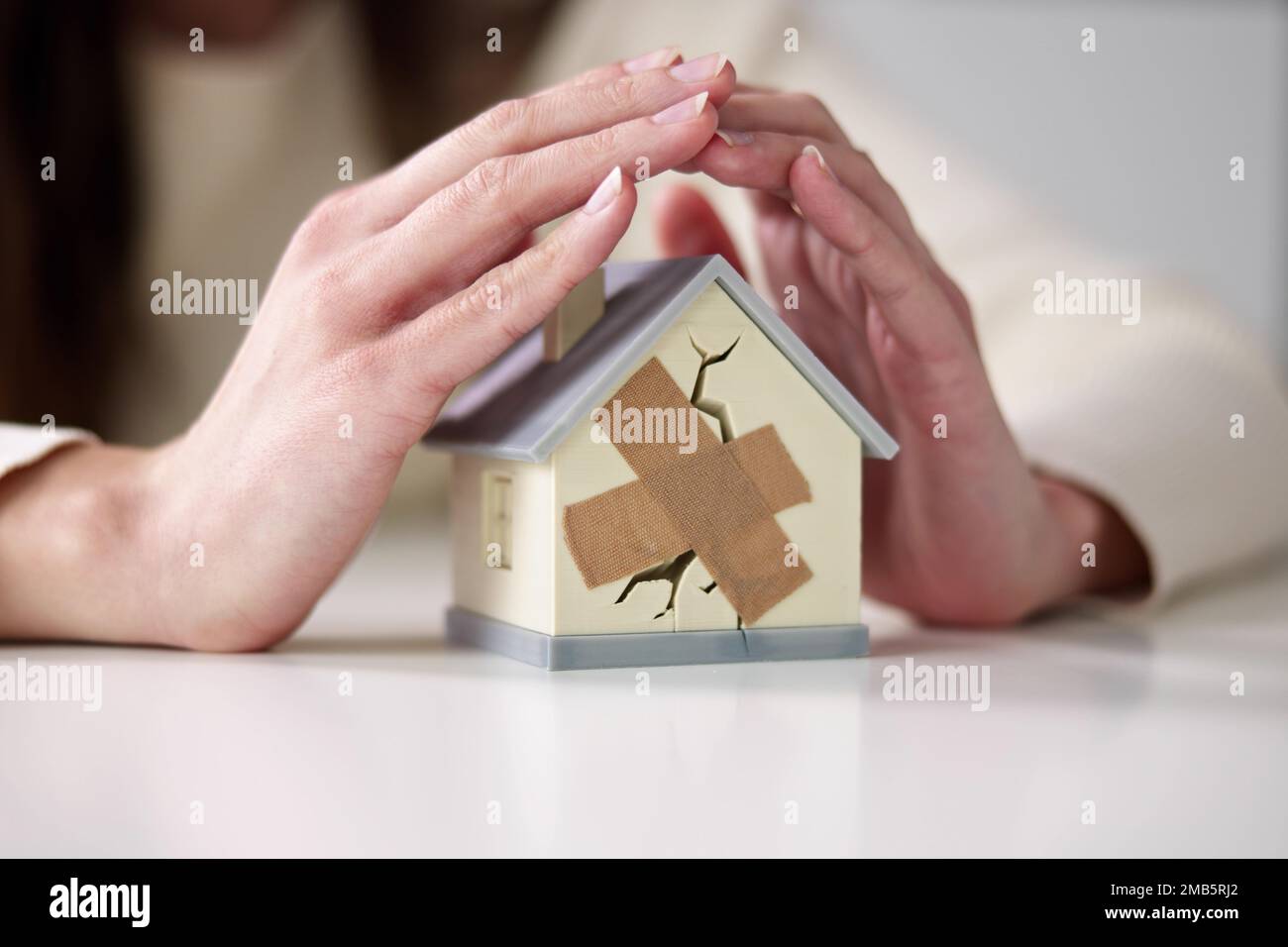 Femme d'affaires protégeant la maison brisée. Dommages immobiliers Banque D'Images