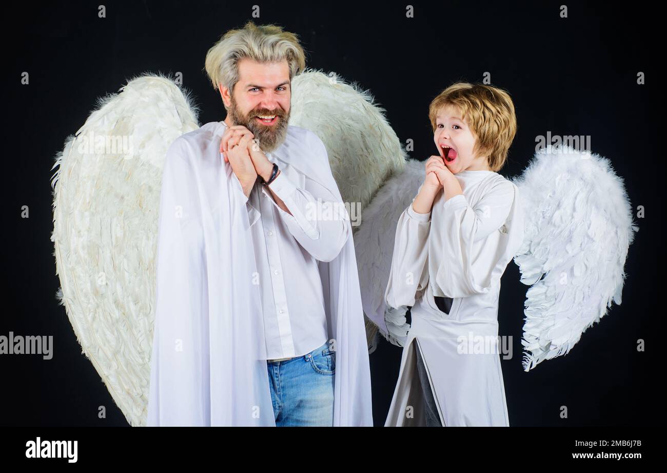 Saint-Valentin. Fils et papa dans des ailes angéliques. Petit cupidon garçon et père en vêtements blancs. Banque D'Images