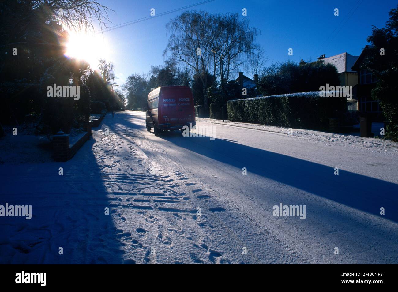Fourgonnette de livraison conduite sur la route glacée dans la neige à l'occasion D'une Sunny Day Surrey, Angleterre Banque D'Images