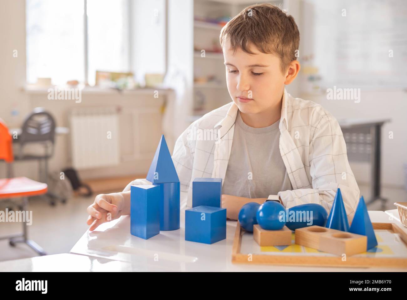 Portrait heureux homme enfant posant avec bois Montessori bleu géométrique volumes figure Banque D'Images