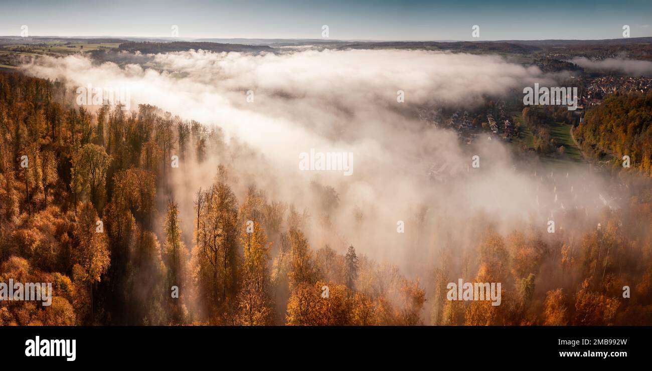 Paysage aérien photographié avec une magnifique brume au-dessus d'une petite ville entourée d'arbres d'automne dorés Banque D'Images