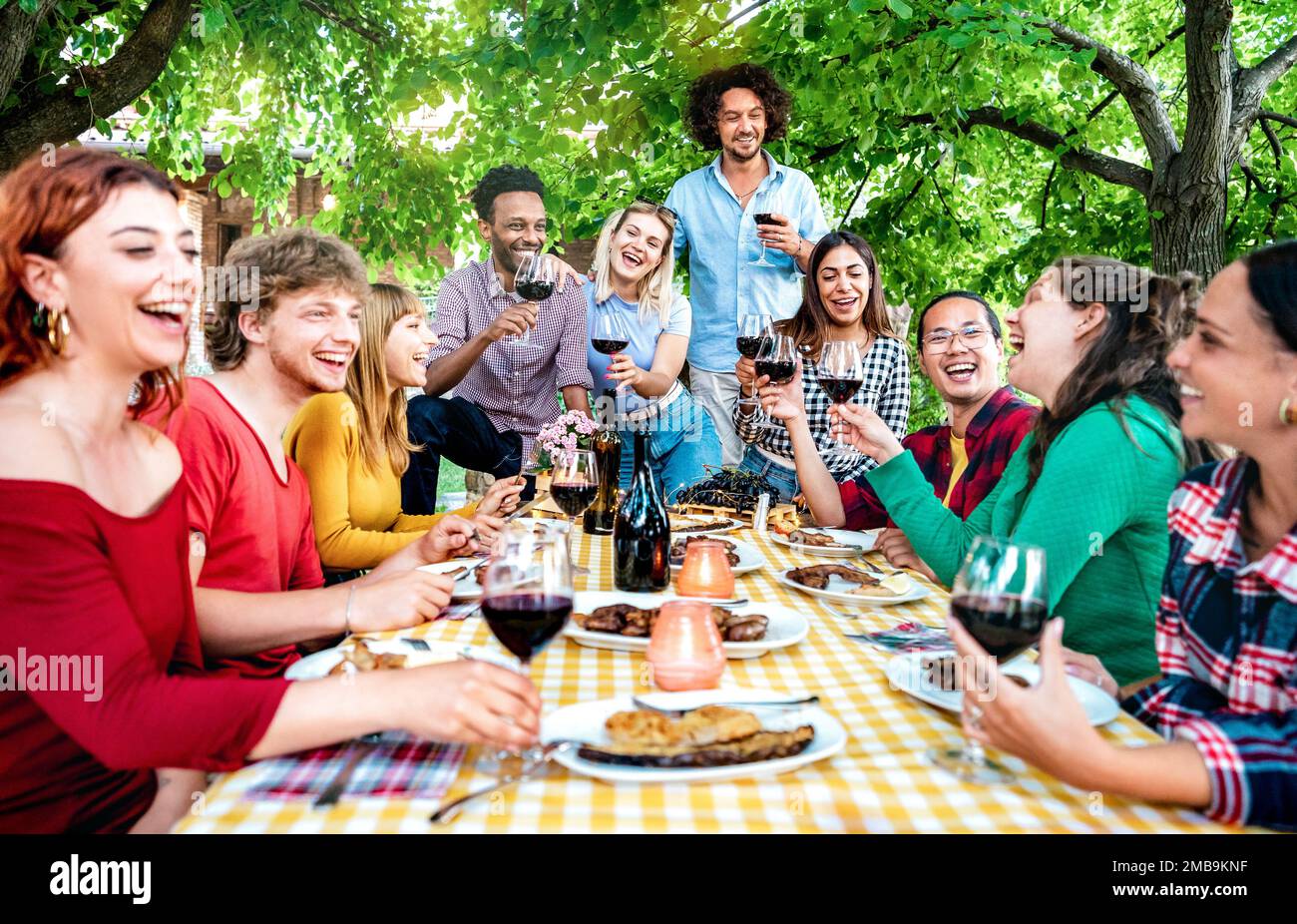 Les gens heureux ayant plaisir à toaster le vin hors maison de ferme latérale - jeunes amis partageant la récolte ensemble à la campagne de vignoble - concept de style de vie de jeunesse Banque D'Images