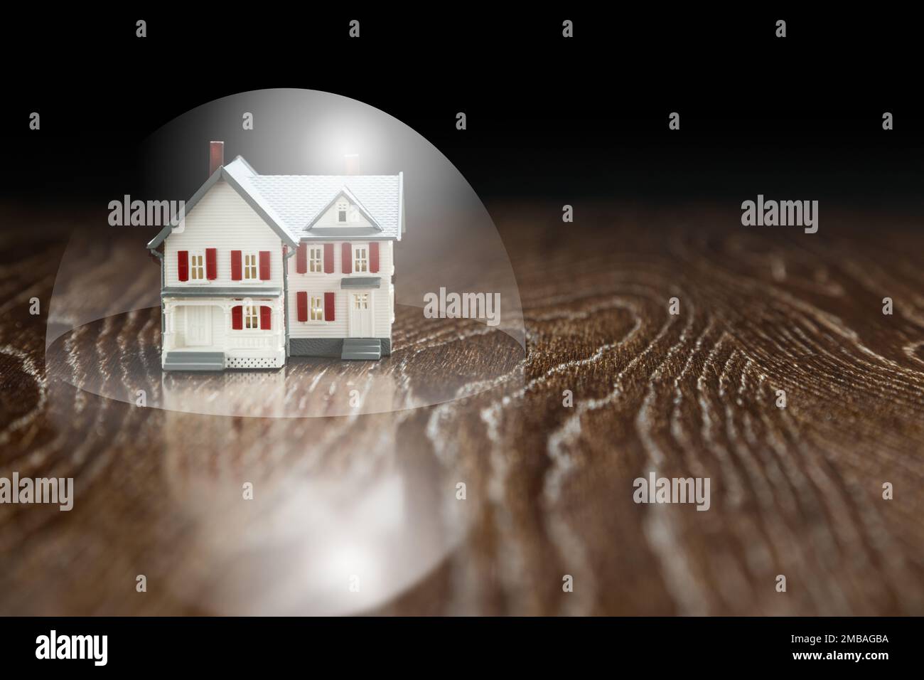 Maison modèle sur une table en bois sous une bulle de protection. Banque D'Images