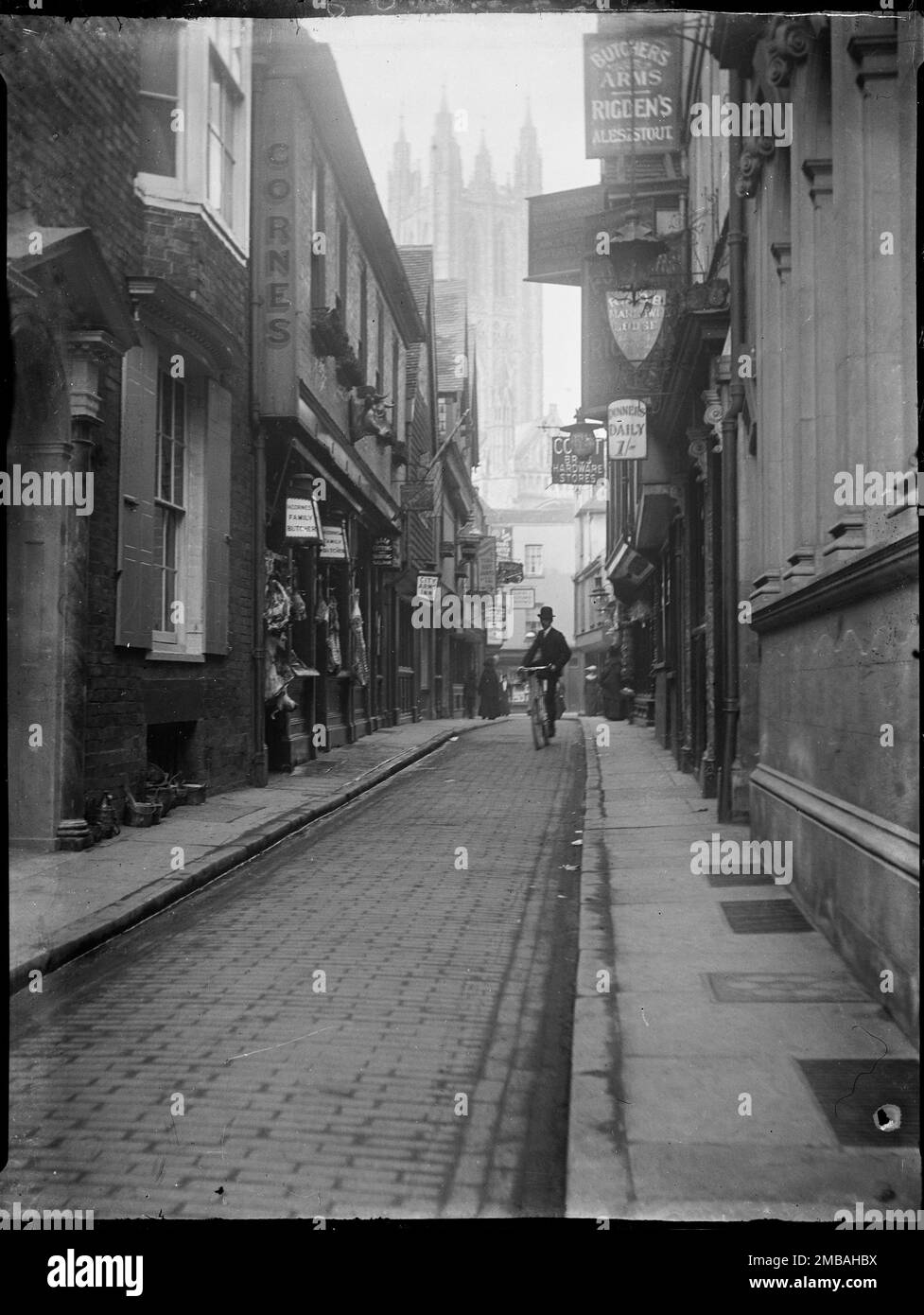 Butchery Lane, Canterbury, Kent, 1904. En regardant le long de la boucherie Lane vers la tour de la cathédrale de Canterbury, montrant des carcasses de viande suspendues à l'extérieur d'un boucherie et un homme faisant du vélo le long de la route. Banque D'Images