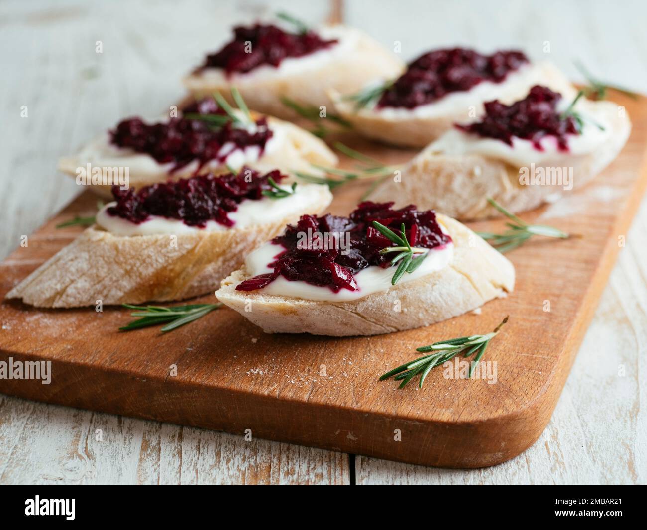 Planche à découper avec une bruschetta maison avec confiture de betteraves et fromage à la crème végétalienne. Banque D'Images