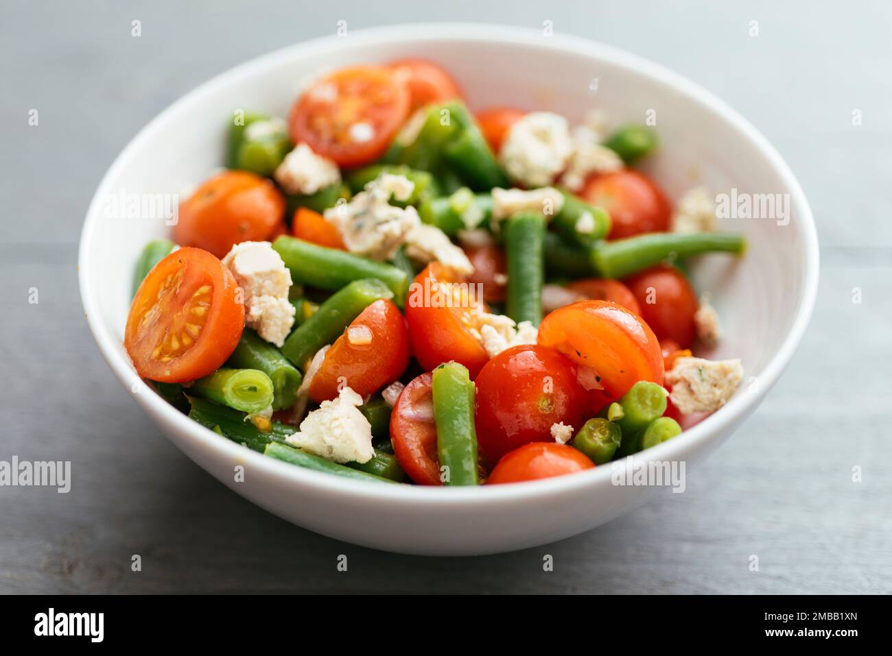 Bol avec une salade de haricots verts et de tomates cerises et du fromage feta vegan maison. Banque D'Images