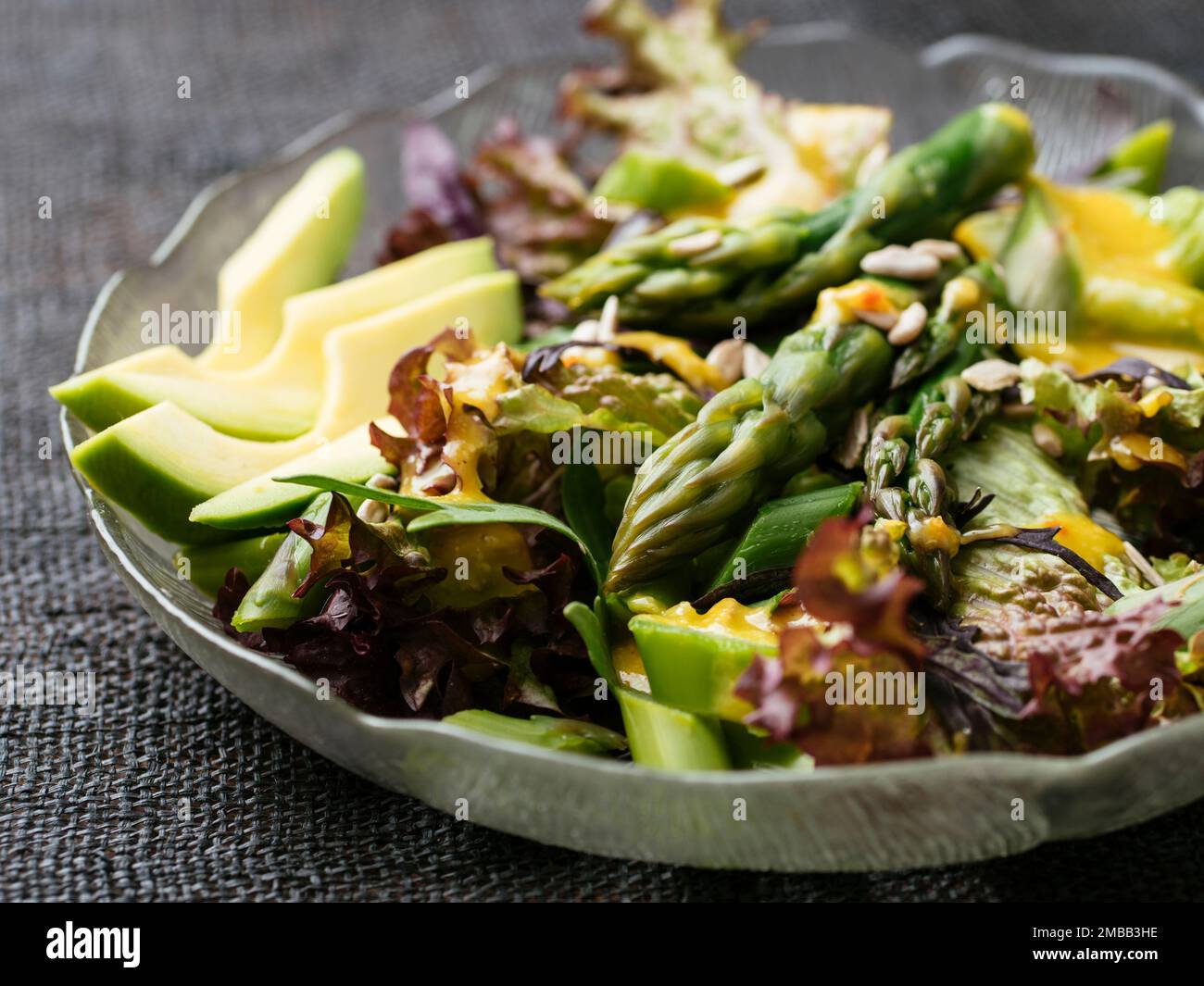 Salade végétalienne avec asperges sur des légumes mélangés avec une vinaigrette tahini. Banque D'Images