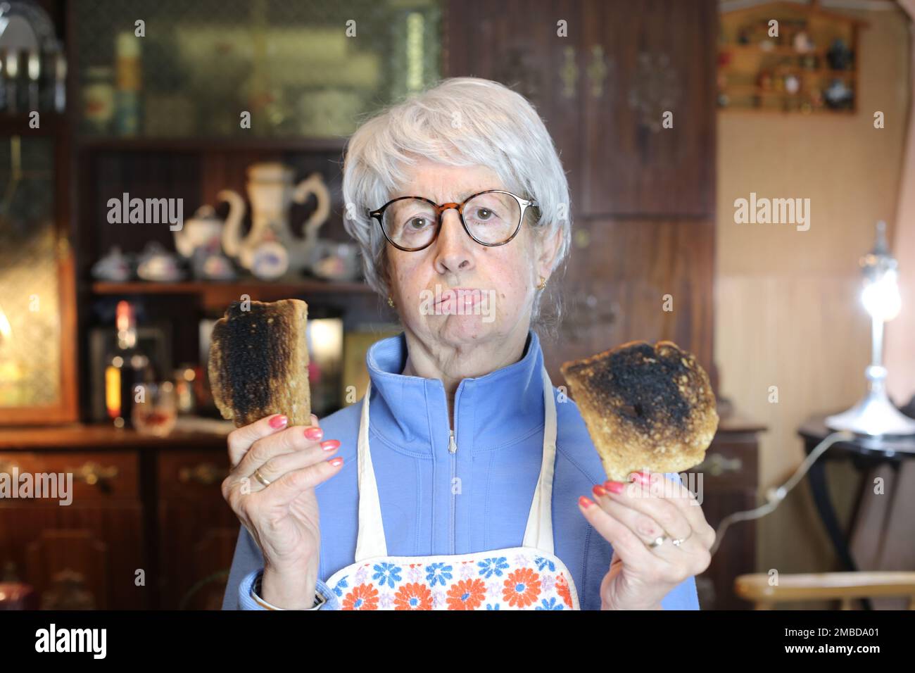 Femme âgée déçue portant des toasts brûlés Banque D'Images