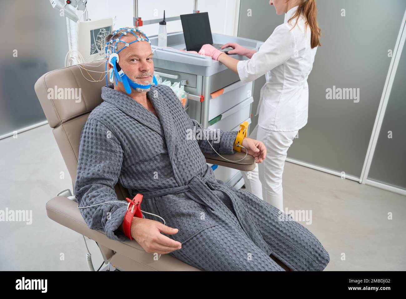 L'homme âgé est assis sur une chaise médicale avec des électrodes sur la tête Banque D'Images