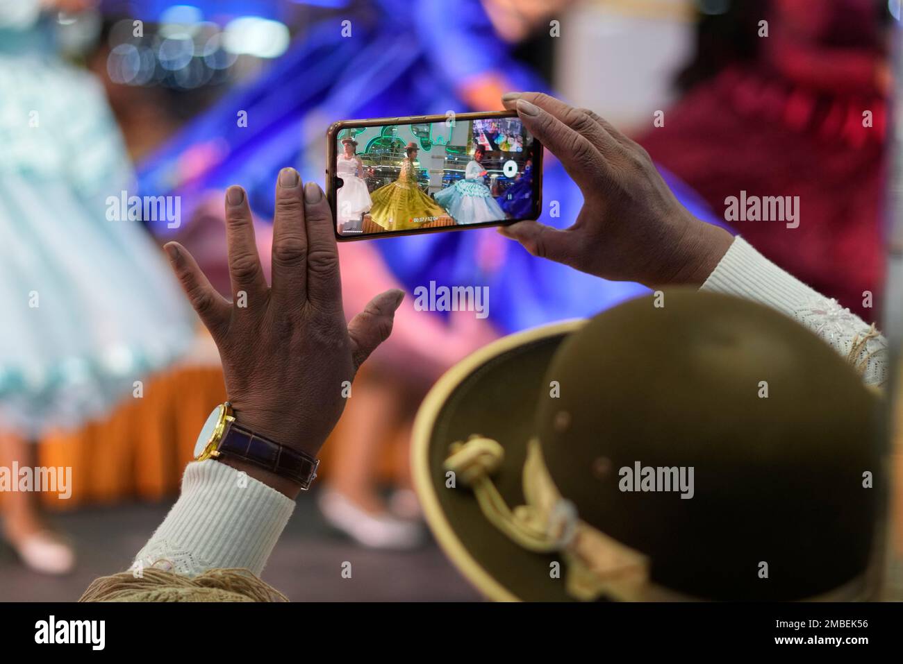 An Aymara woman takes photos during a Cholita fashion show in El Alto, Bolivia, Wednesday, May 18, 2022. Modeling colorful blankets, bowler hats, skirts and jewelry, among other fashions, Bolivian Chola walked the catwalk to boost the economy of dozens of artisans and designers affected by over two years of COVID-19 restrictions. (AP Photo/Juan Karita) Banque D'Images