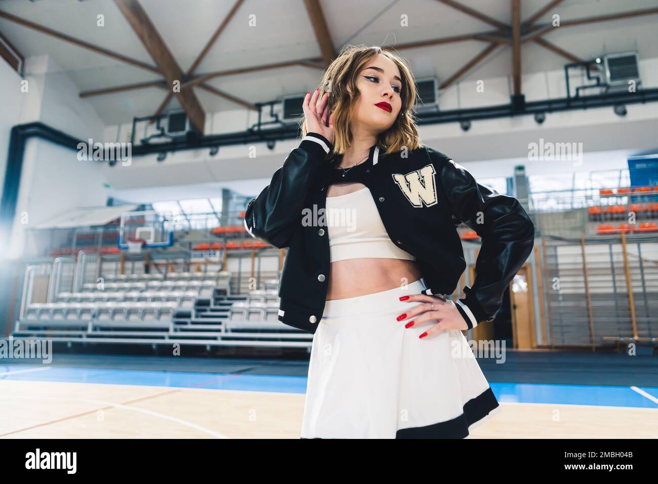 Un meneur portant un uniforme noir et blanc avec un pull noir posé dans une salle de sport. Les supports sont flous en arrière-plan. Photo de haute qualité Banque D'Images